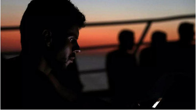  Un migrant cherche à joindre sa famille à bord du navire de l’ONG espagnole « Proactiva Open Arms » alors qu’ils rejoignent le port de Trapani en Sicile. REUTERS/Yannis Behrakis 