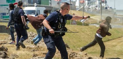  Un CRS pulvérise du gaz lacrymogène sur des migrants à Calais, en juin 2015. (PHILIPPE HUGUEN / AFP) 